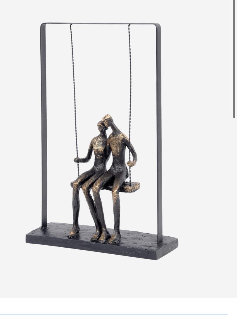 Couple sitting on swing sculpture in bronze finish